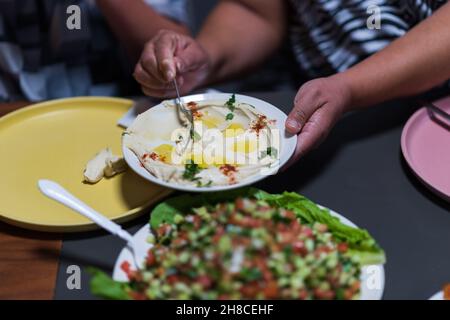 Die Menschen essen zusammen. Ein Tischset mit Köstlichkeiten aus der arabischen Küche. Kichererbsen, Salate, Pitas, gefülltes Gemüse, Fleisch und Huhn. Hochwertige Fotos. Hochwertige Fotos Stockfoto