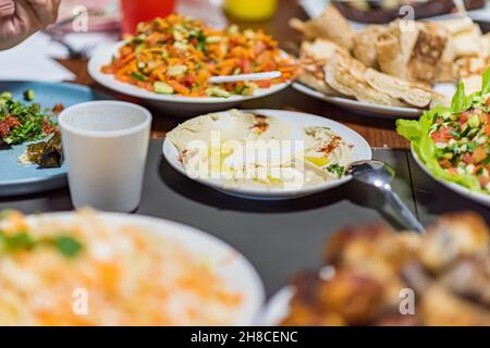 Die Menschen essen zusammen. Ein Tischset mit Köstlichkeiten aus der arabischen Küche. Kichererbsen, Salate, Pitas, gefülltes Gemüse, Fleisch und Huhn. Hochwertige Fotos. Hochwertige Fotos Stockfoto