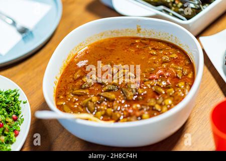 Okra in Tomatensauce. Die Menschen essen zusammen. Ein Tischset mit Köstlichkeiten aus der arabischen Küche. Kichererbsen, Salate, Pitas, gefülltes Gemüse, Fleisch und Huhn. Hochwertige Fotos. Hochwertige Fotos Stockfoto