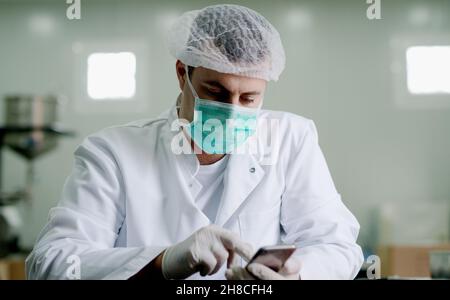 Arzt Schutzkleidung Gesundheitswesen Industrie mit Smartphone. Stockfoto