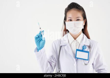 Hübsche junge Ärztin, die eine Spritze mit Impfstoff oder Medizin im Inneren hält Stockfoto