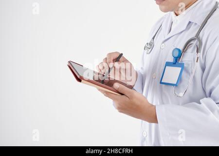 Zugeschnittenes Bild eines ernsthaften Hausarztes, der Notizen auf einem digitalen Tablet gemacht hat Stockfoto
