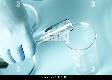 Arzthände in medizinischen Handschuhen mit Kolben. Abstrakter medizinischer Hintergrund im Labor. petrischalen, Reagenzgläser Stockfoto