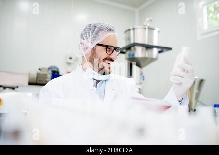 Junge erfolgreiche Technologin, die Gesichtspflegecremes macht. Stockfoto