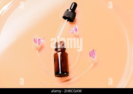 Abstraktes Kosmetiklabor. Flaschen aus dunklem bernsteinfarbenem Glas auf einem beigefarbenen flüssigen Hintergrund. Naturkosmetik für Pflege, Homöopathie. Flach, Draufsicht. Stockfoto