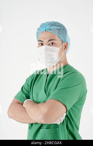 Selbstbewusste männliche Krankenschwester in grünen Peelings trägt medizinische Maske, isoliert auf Shite Stockfoto