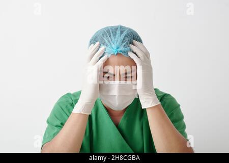 Gestresster verzweifelter Chirurg, der nach dem Verlust des Patienten während der Operation leidet Stockfoto
