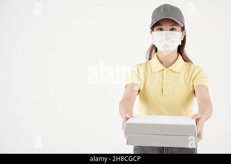 Porträt einer jungen Frau in medizinischer Maske, die Pizza liefert, isoliert auf Weiß Stockfoto
