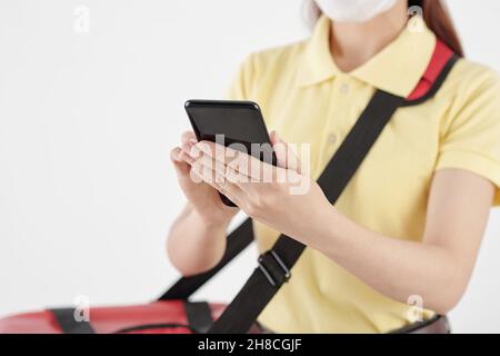 Junge Kurierin, die den Auftrag des Kunden über die Anwendung auf dem Smartphone erhält Stockfoto