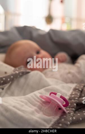 Baby Mädchen mit einem Schnuller auf dem Bett beim mprning Stockfoto