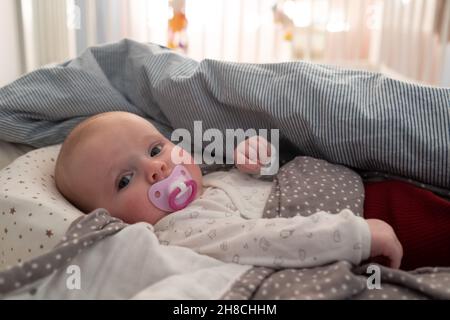 Baby Mädchen mit einem Schnuller auf dem Bett beim mprning Stockfoto