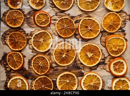 Getrocknete Orangen flach lagen Draufsicht. Hintergrund von natürlichen getrockneten Orangen auf Backpapier. Das Konzept der Vorbereitung auf den Urlaub, Weihnachtsdekorationen. Stockfoto