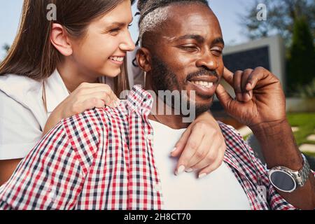 Liebevolle Dame umarmt glücklichen Mann von hinten Stockfoto