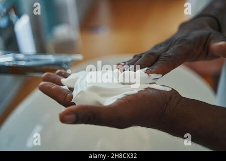 Männchen, der eine Schicht Schaum auf seine Handfläche aufbrachte Stockfoto
