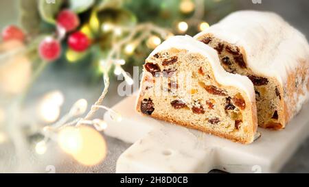Weihnachtsstollen auf blaugrünem festlichem Hintergrund mit Girlande, Weihnachtslichtern und Winterbeeren. Stockfoto