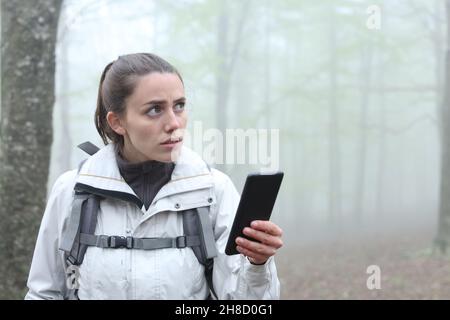 Ich habe den Wanderer mit dem Smartphone verloren, um einen nebligen Tag im Wald zu finden Stockfoto