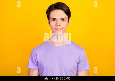 Portrait von attraktiven fröhlichen Inhalt Brünette Kerl trägt violette T-Shirt isoliert über hellen gelben Hintergrund Stockfoto