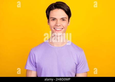 Portrait von attraktiven fröhlichen Inhalt Kerl trägt violette T-Shirt gute offene Stimmung isoliert über hellen gelben Hintergrund Stockfoto