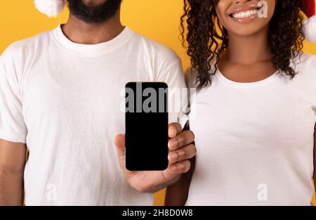 Junges afroamerikanisches Paar zeigt Smartphone mit leerem Bildschirm, demonstriert Webseite oder App, Nahaufnahme Stockfoto