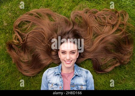 Oben über High-Angle-Ansicht Foto von jungen fröhlichen Mädchen glücklich positives Lächeln liegend Gras Haarpflege genießen Ruhe entspannen im Freien Stockfoto