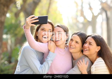 Vier glückliche Freunde, die Selfies mit dem Smartphone auf der Straße machen Stockfoto