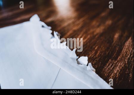 Selektiver Fokus auf gezackte Kanten eines aufgerissenen offenen Briefumschlags Stockfoto