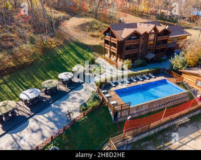 Erholungszentrum im Wald mit einem großen blauen Pool, Sonnenliegen und Tischen. Foto von der Drohne. Stockfoto