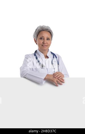 Reife asiatische weibliche Arzt hält leere Banner isoliert auf weißem Hintergrund Stockfoto