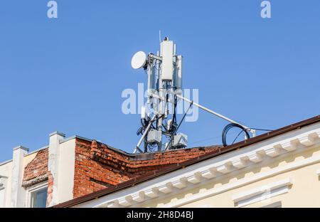 Telekommunikationsturm für Mobiltelefon mit Antennen auf einem Dach des Gebäudes Stockfoto