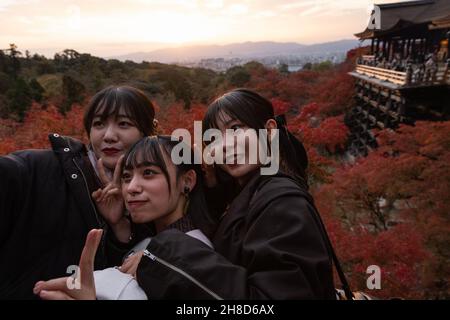 Besucher nehmen Selfies im buddhistischen Tempel Kiyomizu-dera in Kyoto, umgeben von Herbstblättern, auf. Stockfoto