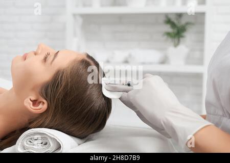 Seitenansicht Nahaufnahme der Kosmetikerin in Gummihandschuhen tun spezielle Verfahren für die Wiederherstellung und Verbesserungen Wachstum Haar. Konzept der Beauty-Injektion für Haare im Salon. Stockfoto