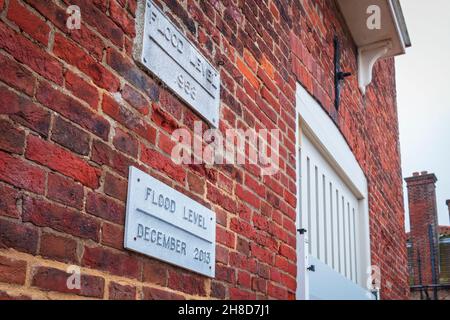 Extreme Wetterereignisse sind nichts Neues: Plaketten, die historische Extreme Tides auf einem Gebäude an der Seite des Hafens in Blakeney, North Norfolk, markieren Stockfoto