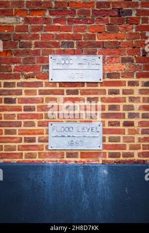 Extreme Wetterereignisse sind nichts Neues: Plaketten, die historische Extreme Tides auf einem Gebäude an der Seite des Hafens in Blakeney, North Norfolk, markieren Stockfoto