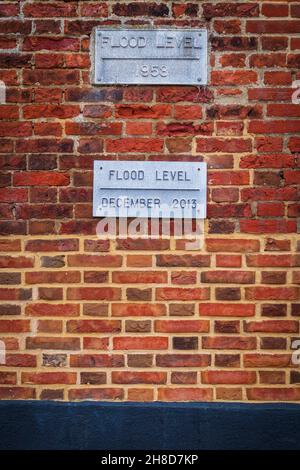 Extreme Wetterereignisse sind nichts Neues: Plaketten, die historische Extreme Tides auf einem Gebäude an der Seite des Hafens in Blakeney, North Norfolk, markieren Stockfoto