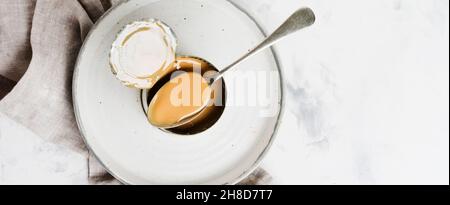 Kondensierte oder verdampfte Milch in offener Dose auf hellem Betontisch. Draufsicht. Stockfoto