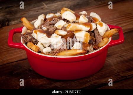 Entenconfit-Poutine-Gericht auf Holztisch Poutine ist eine kanadische Mahlzeit mit pommes Frites-Sauce und Käsekrümmen Stockfoto