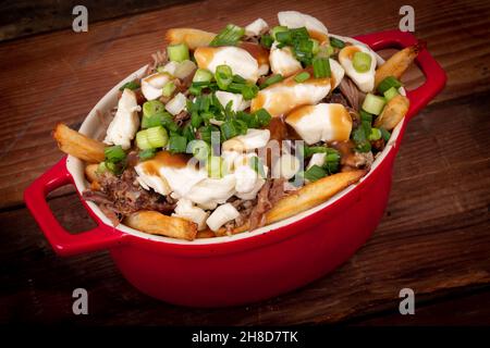 Entenconfit-Poutine-Gericht auf Holztisch Poutine ist eine kanadische Mahlzeit mit pommes Frites-Sauce und Käsekrümmen Stockfoto