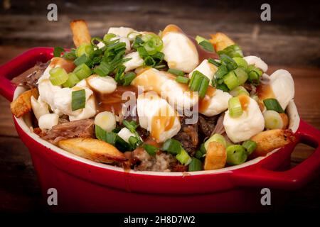 Entenconfit-Poutine-Gericht auf Holztisch Poutine ist eine kanadische Mahlzeit mit pommes Frites-Sauce und Käsekrümmen Stockfoto