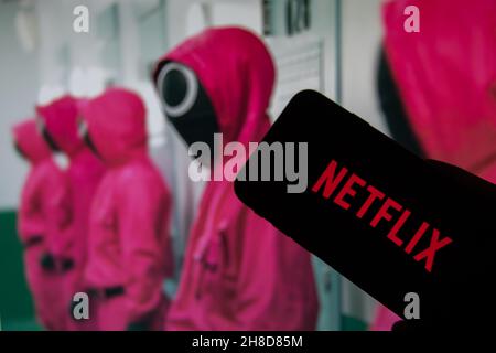 Rheinbach, Deutschland 12. Oktober 2021, das Netflix-Logo auf dem Display eines Smartphones vor einem Fernseher mit der neuen Serie 'Squid Game' ( FOC Stockfoto