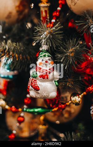 Weihnachtsspielfigur des lustigen Schneemannes, die an den Zweigen des Weihnachtsbaums hängt. Festliche Zauberdetails für das neue Jahr Stockfoto