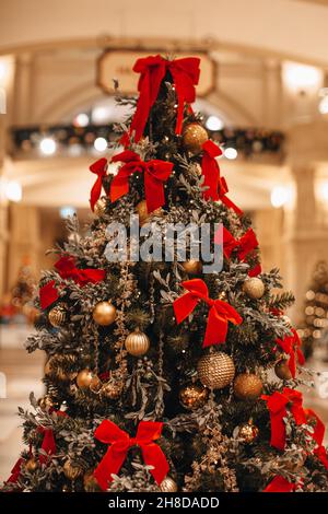 Weihnachtsbaum geschmückt mit goldenen Weihnachtskugeln und roten Schleifen. Magische gemütliche Details, festliche Winterurlaub Hintergrund Stockfoto