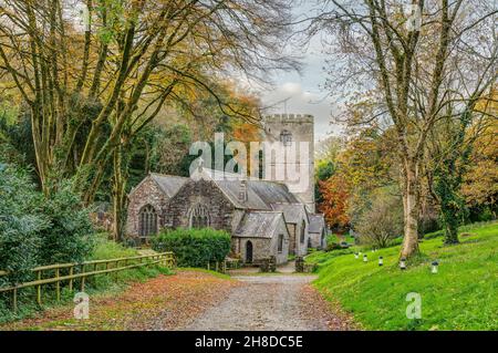 Eine typisch englische Kulisse einer sehr alten, aus Stein erbauten Dorfkirche, die in einem sehr hübschen, von Bäumen gesäumten Tal mit einer wunderschönen Farbe im Spätherbst sitzt. Stockfoto