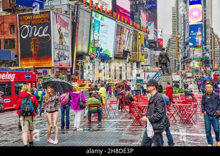 NEW YORK, USA - 10. JUNI 2013: Menschen besuchen den NY Times Square im Regen. Der Times Square hat jährlich mehr als 39 Millionen Besucher. Es ist ein wichtiger Meilenstein Stockfoto