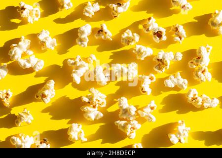 Knackiges, verstreutes Popcorn auf gelbem Hintergrund, Draufsicht. Das beste Essen für das Kino Stockfoto