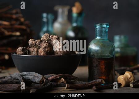 Flaschen mit Infusion oder Tinktur von Persicaria bistorta und gemeinsamen Beinwell-Wurzeln. Schale mit Bistort, Schlangenwurzeln, Schlangenwurzeln. Trockene comfrey officinalis Wurzel Stockfoto