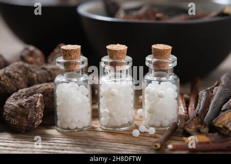 Drei Flaschen homöopathisches Granulat. Persicaria bistorta und gemeinsame Beinwell oder symphytum officinale Wurzeln. Konzept der Homöopathie. Stockfoto