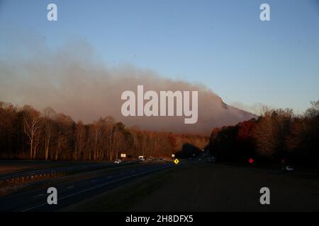 Pinnacle, North Carolina, USA. 29th. November 2021. Der Knauf des Pilot Mountain State Park, der am meisten von der Hand liegt, wurde an einem ansonsten klaren Morgen von einem Rauchschwaden umhüllt. Das Feuer, das am Samstagnachmittag auf einem beliebten Pfad im Pilot Mountain State Park ausging, wurde von trockenen und windigen Bedingungen angefacht und umfasste mehr als 250 Hektar, was die Camper dazu zwang, den Park zu evakuieren und für die absehbare Zukunft zu schließen. (Bild: © Bob Karp/ZUMA Press Wire) Stockfoto