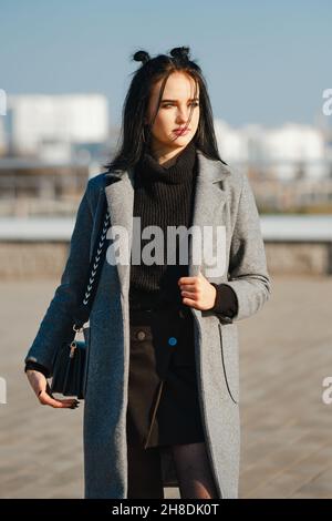 Junge Frau im warmen Mantel und Pullover auf der Straße Stockfoto