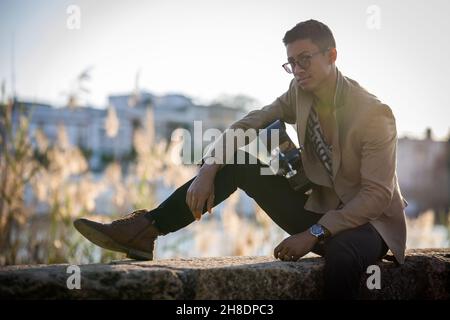 Latin-Mann Gitarrist posiert auf der Straße während des Sonnenuntergangs gegen Licht Stockfoto
