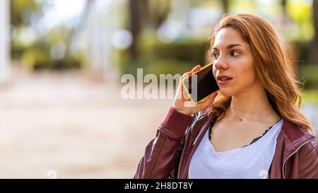 Junge natürliche Mädchen im Park im Gespräch mit ihrem Smartphone Stockfoto